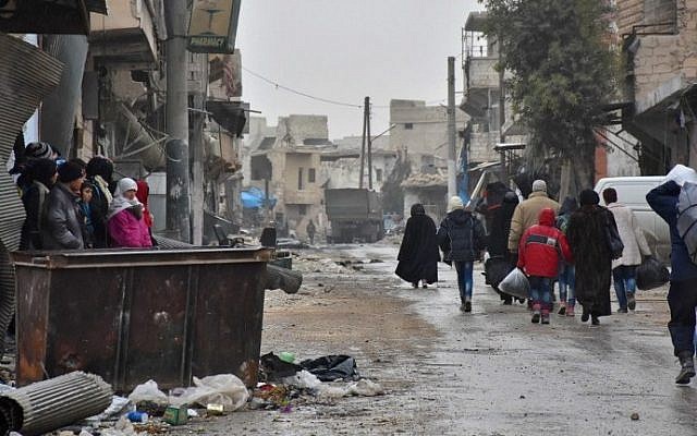 Syrian residents fleeing the eastern part of Aleppo walk through a street in Masaken Hanano, a former rebel-held district which was retaken by the regime forces last week, on November 30, 2016. (AFP Photo/George Ourfalian)
