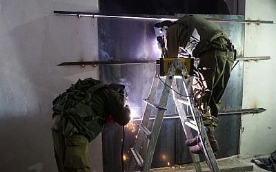 Israeli soldiers weld shut a workshop allegedly used to manufacture illegal guns in Yatta, outside Hebron, early in the morning on November 8, 2016. (IDF Spokesperson's Unit)
