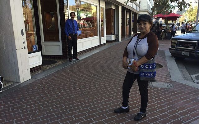 Alicia Ramirez, 67, hands out fliers to passersby on a busy street in a largely Latino area lined with money transfer businesses and shops selling elegant gowns for quinceanera celebrations in Santa Ana, California on Wednesday, Nov. 9, 2016. (AP Photo/Amy Taxin) Alicia Ramirez, 67, hands out fliers to passersby on a busy street in a largely Latino area lined with money transfer businesses and shops selling elegant gowns for quinceanera celebrations in Santa Ana, California on Wednesday, Nov. 9, 2016. (AP Photo/Amy Taxin)