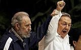 Fidel Castro, left, raises the hand of his brother, Cuban President Raul Castro, center, as they sing the anthem of international socialism during the 6th Communist Party Congress in Havana, Cuba on April 19, 2011. (AP Photo/Javier Galeano, File)