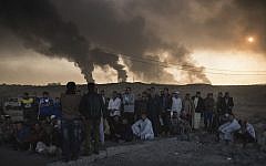 Men are held by Iraqi national security agents, to be interrogated at a checkpoint, as oil fields burn in Qayara, south of Mosul, Iraq, Saturday, Nov. 5, 2016.  (AP Photo/Felipe Dana)