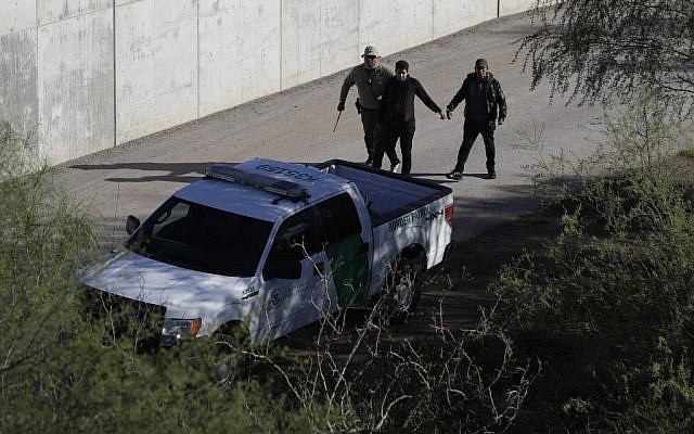 In this Wednesday, Nov. 16, 2016, photo, a US Customs and Border Patrol agent walks with suspected immigrants caught entering the country illegally along the Rio Grande in Hidalgo, Texas. (AP Photo/Eric Gay)