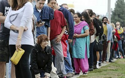 In this Oct. 30, 2016 file photo, a woman kneels to take a "back break" while waiting in line at a weekend early voting polling place at the North Hollywood branch library in Los Angeles, California. (AP Photo/Reed Saxon, File)