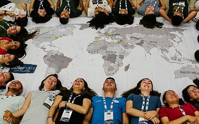Diller Teen Fellows surround a map, illustrating the global partnership component of the teen leadership program. (Diller Teen Fellows)