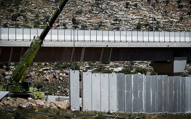 Israeli machines and workers build parts of the Israeli security barrier near the West Bank city of Beit Jala, outside Jerusalem, on April 17, 2016. (Wisam Hashlamoun/FLASH90)