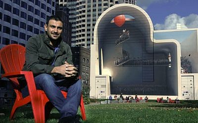 In this Friday, Nov. 11, 2016 photo, Mehdi Ghadyanloo, from Tehran, Iran, poses with his mural, "Spaces of Hope," on the Rose Kennedy Greenway in Boston. (AP Photo/Bill Sikes)