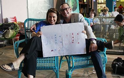 Hadass Tesher and Fred Menachem, supporters of Democratic candidate Hillary Clinton hold up a Hebrew 'I'm with her' sign during a 'Democrats in Israel' election results viewing party in Tel Aviv's Abraham Hostel on November 9, 2016. (Judah Ari Gross/Times of Israel)