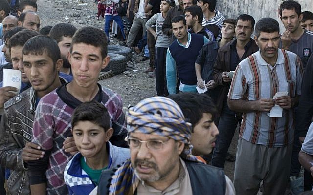 People queue to receive aid packages in Gogjali, on the eastern edge of Mosul, Iraq, Thursday, Nov. 3, 2016. (AP Photo/Marko Drobnjakovic)