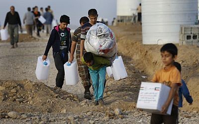 Displaced Iraqi boys, who fled from Mosul with their families, carry food and other aid supplies, at a camp for internally displaced people in Hassan Sham, east of Mosul, Iraq, Saturday, Nov. 12, 2016.  (AP Photo/Hussein Malla)