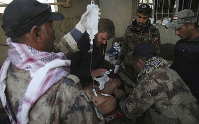 Iraqi special forces soldiers from the medical unit, and an American medic volunteer, center left, treat an injured man who was wounded by a mortar shell at a field hospital, in the Samah front line neighborhood, in Mosul, Iraq, Sunday, Nov. 27, 2016. (AP Photo/Hussein Malla)