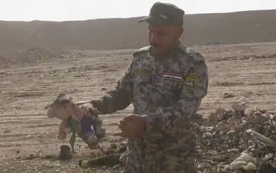 In this Monday, Nov. 7, 2016 frame grab from video, an Iraqi federal police officer holds a stuffed toy at the site of a mass grave in Hamam al-Alil, Iraq. (AP Photo) In this Monday, Nov. 7, 2016 frame grab from video, an Iraqi federal police officer holds a stuffed toy at the site of a mass grave in Hamam al-Alil, Iraq. (AP Photo)