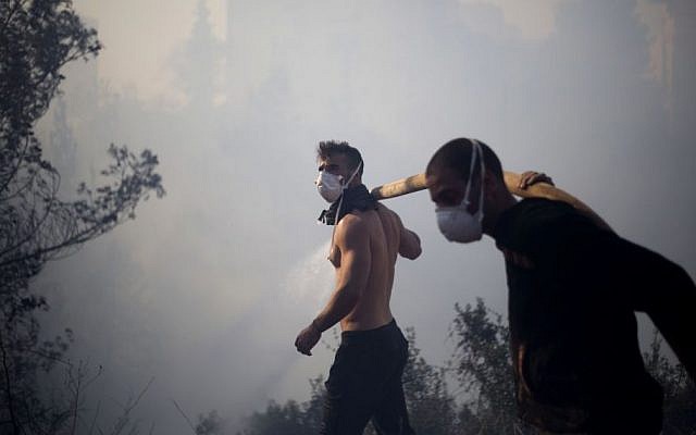 Residents fight a wildfire in Haifa, Israel, Thursday, Nov. 24, 2016. The blaze ripped through parts of Israel's third-largest city, forcing tens of thousands of people to evacuate their homes (AP Photo/Ariel Schalit)
