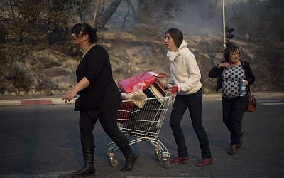 People carry their belongings inside a supermarket cart as they evacuate from wildfires in Haifa, Israel, Thursday, Nov. 24, 2016.  (AP Photo/Ariel Schalit)