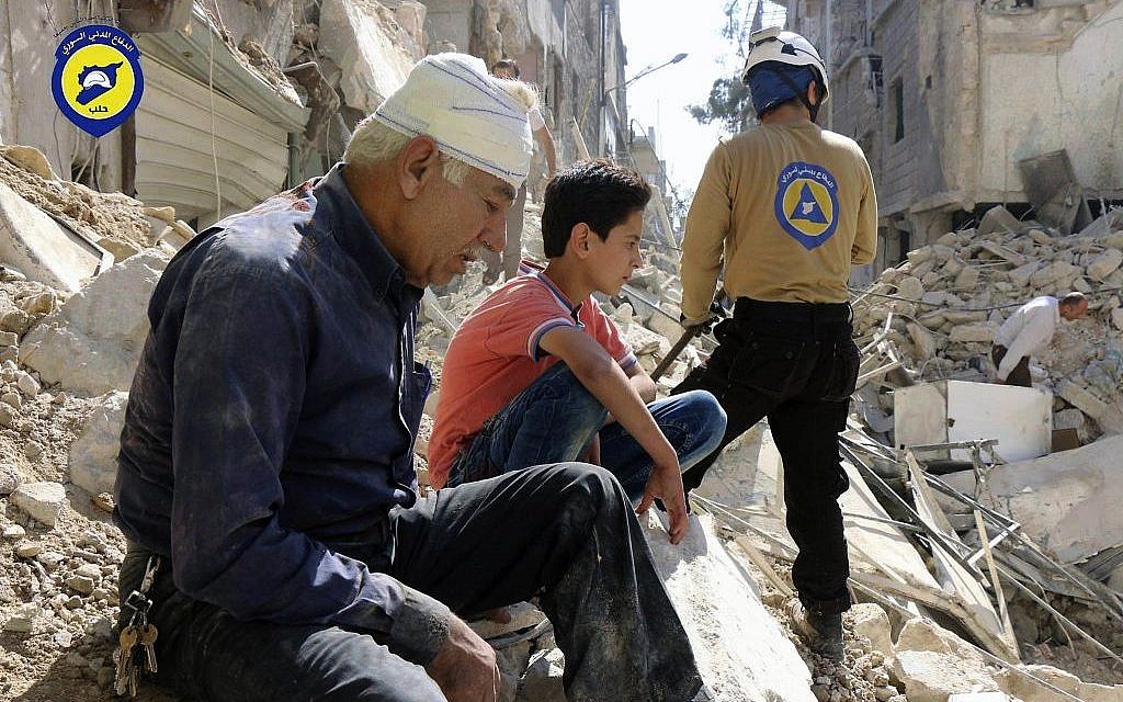 Residents sit among rubble in rebel-held eastern Aleppo, Syria, October 11, 2016. (Syrian Civil Defense- White Helmets via AP, File)