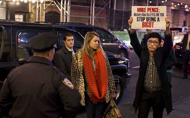 A protester holds a placard as he waits for Vice President-elect Mike Pence to leave the Richard Rodgers Theatre after a performance of "Hamilton," in New York, Friday, Nov. 18, 2016. (AP Photo/Andres Kudacki)