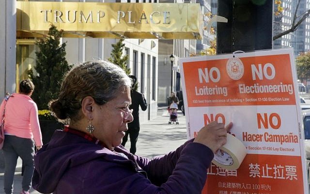 In this Nov. 8, 2016 file photo, poll interpreter Mayra Mora affixes a sign outside of a polling place in an apartment building named for then Republican presidential candidate Donald Trump, in New York. (AP/Richard Drew) In this Nov. 8, 2016 file photo, poll interpreter Mayra Mora affixes a sign outside of a polling place in an apartment building named for then Republican presidential candidate Donald Trump, in New York. (AP/Richard Drew)