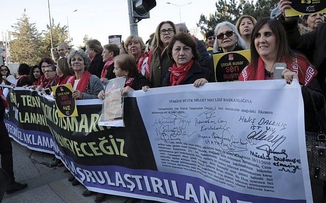 Women hold a banner as thousands of members of Turkey's main opposition Republican People's Party march to the parliament in Ankara, Turkey, Tuesday, Nov. 22, 2016. The banner with the names of ruling party lawmakers who signed the law project reads: " We will not let you to pardon rapists." (AP Photo/Burhan Ozbilici)