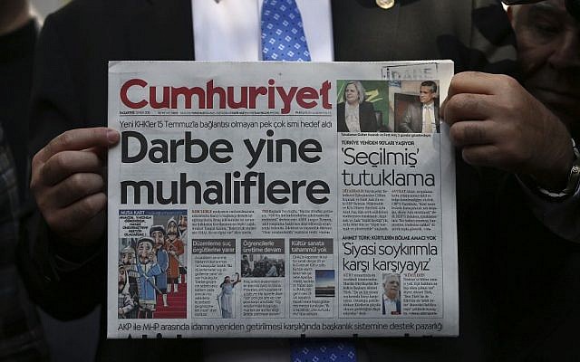 A man holds the latest copy of the Cumhuriyet newspaper outside its Istanbul headquarters after police detained chief editor Murat Sabuncu and two columnists of the opposition newspaper, October 31, 2016. (AP Photo/Emrah Gurel)