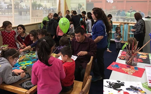 Member's of Berlin's Jewish community volunteer with refugee children at the Spandau refugee center, with arts and crafts in front and face painting in back. November 13, 2016. (Courtesy)