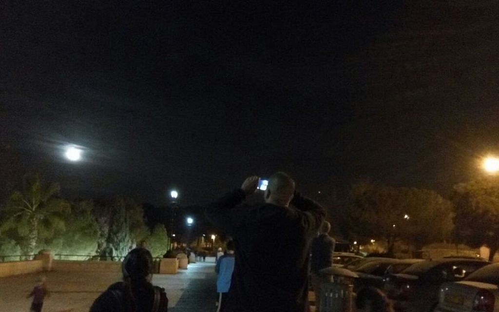 An Israeli man takes a picture of the 'supermoon' on Jerusalem's promenade on November 14, 2016. (Joshua Davidovich/Times of Israel)