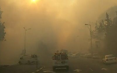 An ambulance makes its way through the smoke-filled streets of Haifa as firefighters battle to control a massive blaze across the city on November 24, 2016 (screen capture: Channel 10)