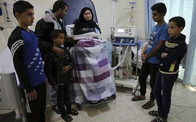 In this November 1, 2016 photo, Syrian refugee Kholoud Foura, who has developed muscular dystrophy, poses with her husband and their children, while tied to the bed and hooked up to a respirator, at Al-Wafa hospital, in Al Zahra City, central Gaza Strip. The family have slept in beds and mattresses in her hospital room for about a year and a half. (AP Photo/Adel Hana) In this November 1, 2016 photo, Syrian refugee Kholoud Foura, who has developed muscular dystrophy, poses with her husband and their children, while tied to the bed and hooked up to a respirator, at Al-Wafa hospital, in Al Zahra City, central Gaza Strip. The family have slept in beds and mattresses in her hospital room for about a year and a half. (AP Photo/Adel Hana)