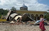 Illustrative. An Acehnese girl walks past a collapsed mosque minater following an earthquake in Pidie, Aceh province, Indonesia,  on December 7, 2016. (AFP PHOTO/CHAIDEER MAHYUDDIN)