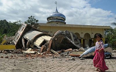 Illustrative. An Acehnese girl walks past a collapsed mosque minater following an earthquake in Pidie, Aceh province, Indonesia,  on December 7, 2016. (AFP PHOTO/CHAIDEER MAHYUDDIN)