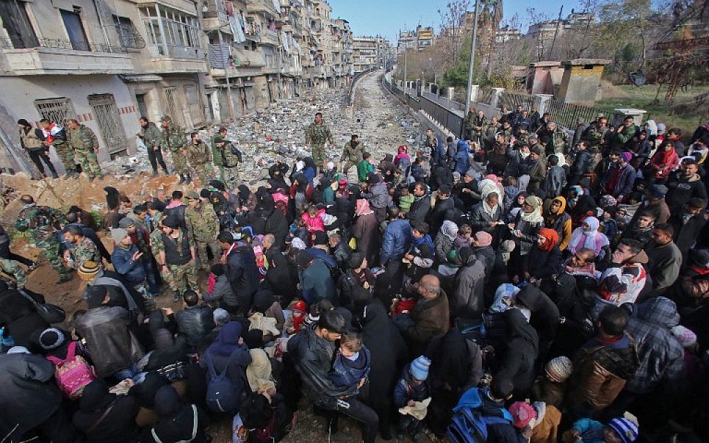 Syrian residents fleeing the violence in Aleppo gather at a checkpoint manned by pro-government forces in the Maysaloun neighborhood of the city on December 8, 2016. (AFP PHOTO/Youssef KARWASHAN)