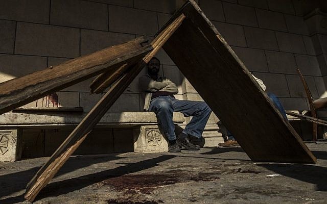 An Egyptian man sits at the scene of a bomb explosion that targeted the Saint Peter and Saint Paul Coptic Orthodox Church on December 11, 2016, in Cairo's Abbasiya neighborhood. (AFP PHOTO / KHALED DESOUKI)