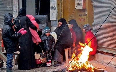 Syrians keep warm next to a fire in Aleppo's Fardos neighborhood, after fleeing violence in the restive Bustan al-Qasr neighborhood, on December 13, 2016. (AFP PHOTO/STRINGER)