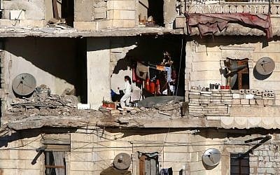 Residents in a government-held part of Aleppo's Salaheddin neighborhood watch as buses evacuate rebel fighters and their families from rebel-held neighbourhoods in Syria's northern embattled city on December 15, 2016. (AFP/Youssef Karwashan)