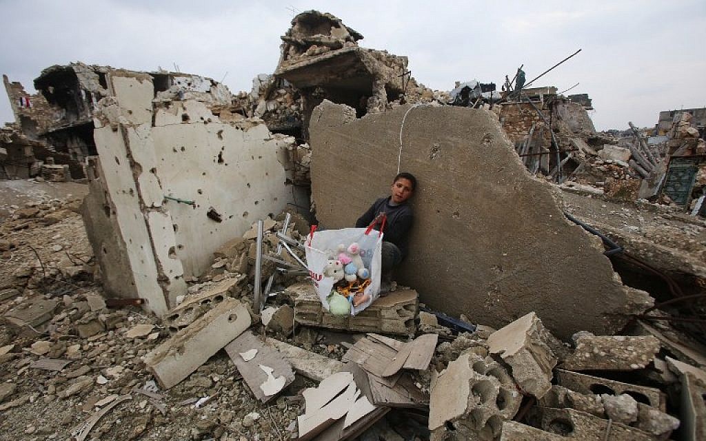A Syrian boy sits with belongings he collected from the rubble of his house in Aleppo on December 17, 2016, after pro-government forces retook the area from rebel fighters. (AFP/Youssef KARWASHAN)