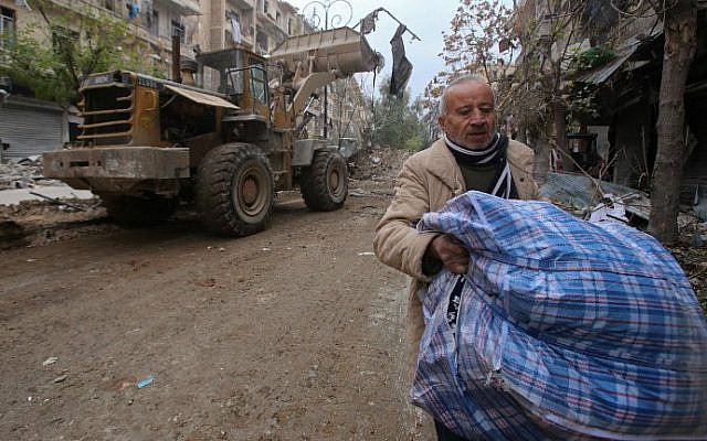 A Syrian man walks past a bulldozer removing rubble from a road as Syrian pro-government forces re-open a street in Aleppo's old city that was formerly barricaded, dividing the government-held and rebel-held areas, on December 17, 2016.
(Youssef Karwashan/AFP) A Syrian man walks past a bulldozer removing rubble from a road as Syrian pro-government forces re-open a street in Aleppo's old city that was formerly barricaded, dividing the government-held and rebel-held areas, on December 17, 2016.
(Youssef Karwashan/AFP)