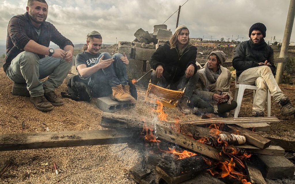 Young Israeli settlers gather around a fire in the settlement outpost of Amona on December 18, 2016. (AFP/JACK GUEZ)