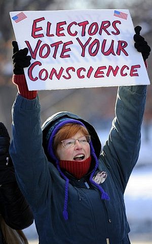 Gloria McVeigh, 65, holds a sign and cheers during a demonstration against US President-elect Donald Trump on the eve of the Electoral College vote, in Denver, Colorado on December 18, 2016. (AFP/ Chris Schneider)