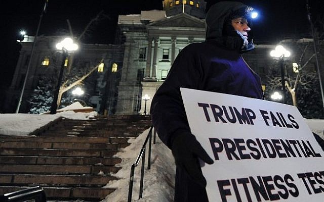 Dave Barnkow, 58, holds a sign during a demonstration against US President-elect Donald Trump outside the Colorado Capitol building on the eve of the Electoral College vote, in Denver, Colorado on December 18, 2016. (AFP/ Chris Schneider)