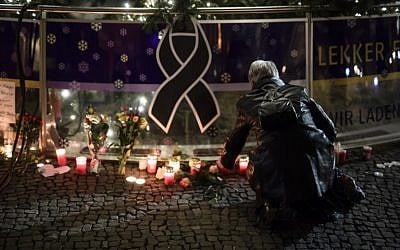A woman lights a candle underneath the Christmas Tree near the Brandenburg Gate in Berlin on December 20, 2016 one day after a truck crashed into a Christmas market. (AFP/CLEMENS BILAN)
