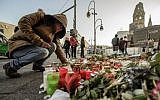 A mourner places a candle on December 21, 2016, at a makeshift memorial near the Kaiser Wilhelm Memorial Church in Berlin, close to the site where a truck crashed into a Christmas market two days before. (AFP Photo/Clemens Bilan)