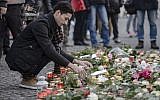 An Iraqi refugee lays a flower at a makeshift memorial near the Kaiser-Wilhelm-Gedaechtniskirche (Kaiser Wilhelm Memorial Church) in Berlin, close to the site where a truck crashed into a Christmas market two days before, on December 21, 2016 in Berlin. (AFP/Clemens Bilan)