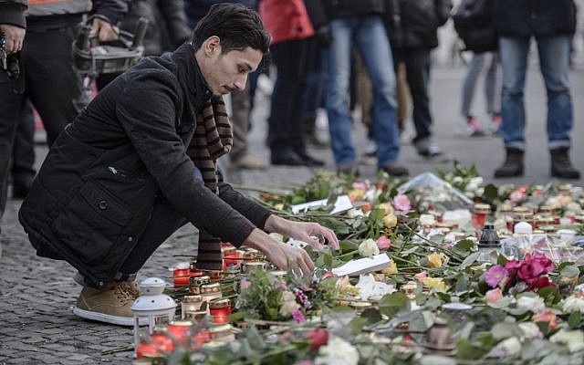 An Iraqi refugee lays a flower at a makeshift memorial near the Kaiser-Wilhelm-Gedaechtniskirche (Kaiser Wilhelm Memorial Church) in Berlin, close to the site where a truck crashed into a Christmas market two days before, on December 21, 2016 in Berlin. (AFP/Clemens Bilan) An Iraqi refugee lays a flower at a makeshift memorial near the Kaiser-Wilhelm-Gedaechtniskirche (Kaiser Wilhelm Memorial Church) in Berlin, close to the site where a truck crashed into a Christmas market two days before, on December 21, 2016 in Berlin. (AFP/Clemens Bilan)