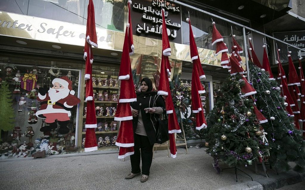 A woman stands outside a shop selling Christmas ornaments and decorations in Gaza City on December 22, 2016. (AFP Photo/Said Khatib)
