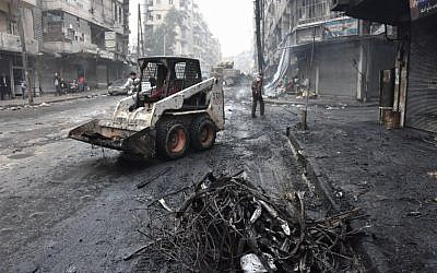 A tractor removes rubble as the Syrian government starts to clean up areas formerly held by opposition forces in the northern city of Aleppo on December 27, 2016, in the Shaar district. (AFP/George Ourfalian)