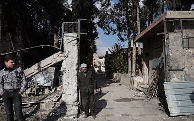 A Syrian boy and a school guard stand outside a school in the rebel-held town of Douma, on the eastern outskirts of Damascus, on December 30, 2016, on the first day of a nationwide truce. (Abd Doumany/AFP)