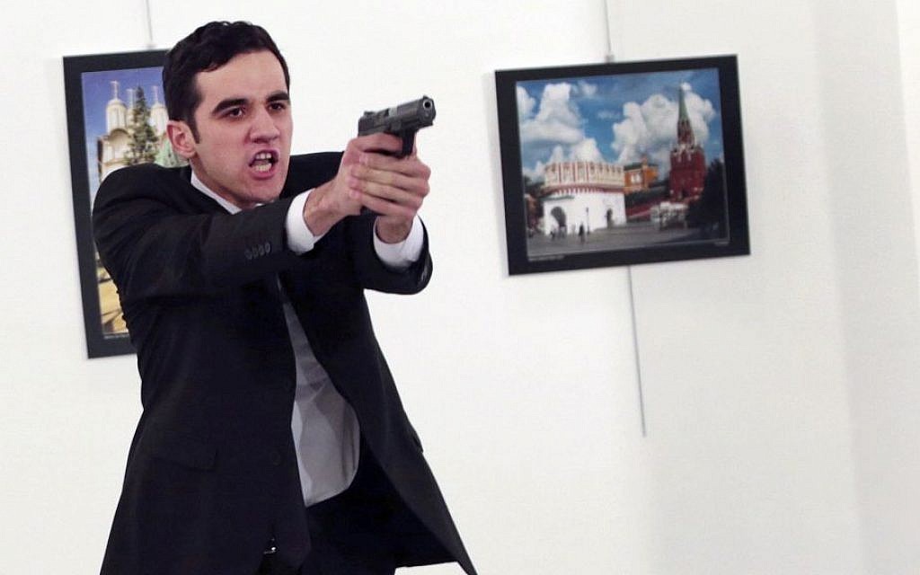 A man identified as Mevlut Mert Altintas holds up a gun after shooting Andrei Karlov, the Russian ambassador to Turkey, at a photo gallery in Ankara, Turkey, December 19, 2016. (AP/Burhan Ozbilici)