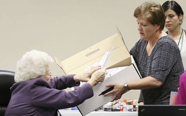 County Clerk Brenda Jaszewski holds a box of absentee ballots from the town of Erin, Wisconsin, as Board of Canvass member Marilyn Merten reaches to take a ballot out during a statewide presidential election recount, Thursday, Dec. 1, 2016, West Bend, Wisconsin. (John Ehlke/West Bend Daily News via AP)