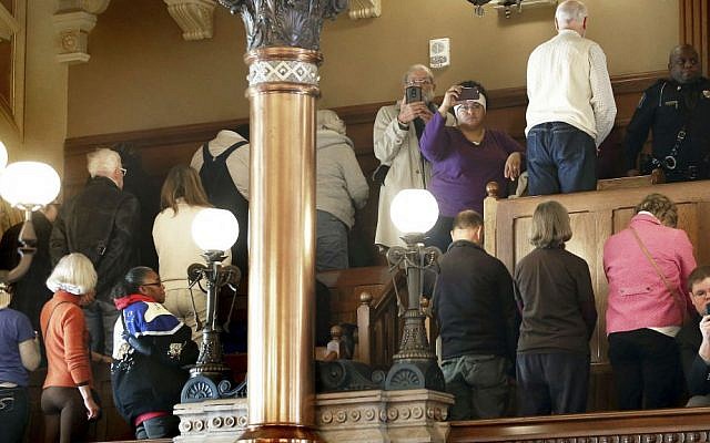 People turn their backs on Electoral College members Monday, Dec. 19, 2016, at the state Capitol as they vote in Topeka, Kansas. Kansas's six Republican members of the Electoral College cast their ballots for President-elect Donald Trump, keeping with the state's popular vote. (Thad Allton/The Topeka Capital-Journal via AP)