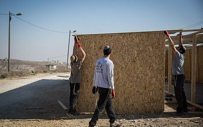 Young Jewish men seen building a structure in the Jewish settlement of Amona in the West Bank, on November 28, 2016. (Hadas Parush/Flash90)