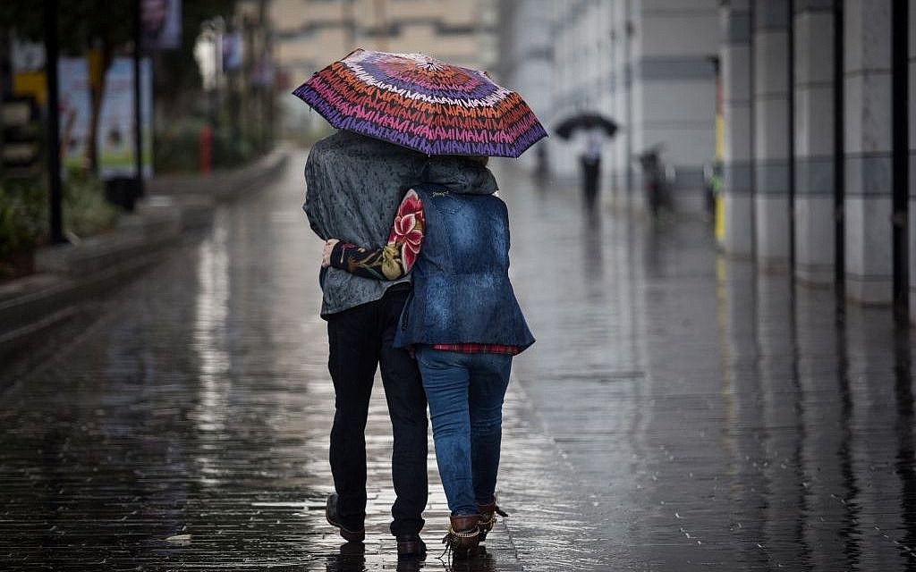 Illustrative: A couple walks with an umbrella in the rain in Tel Aviv, on December 1, 2016. (Nati Shohat/Flash90)
