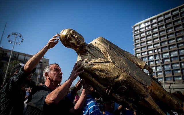 A golden statue of Prime Minister Benjamin Netanyahu is toppled in Rabin Square in Tel Aviv on December 6, 2016, hours after it was placed overnight by artist Itay Zalait, without permission from the Tel Aviv municipality. (Miriam Alster/Flash90) A golden statue of Prime Minister Benjamin Netanyahu is toppled in Rabin Square in Tel Aviv on December 6, 2016, hours after it was placed overnight by artist Itay Zalait, without permission from the Tel Aviv municipality. (Miriam Alster/Flash90)